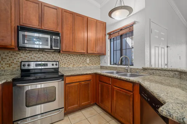 a kitchen with granite countertop stainless steel appliances a stove microwave and sink