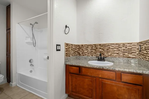 a bathroom with a granite countertop sink a toilet and shower