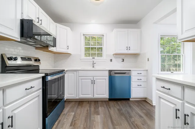 a kitchen with cabinets appliances a sink and a window