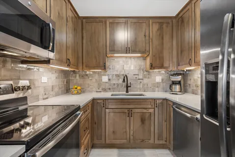 a kitchen with stainless steel appliances granite countertop a sink a stove and a refrigerator