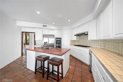 a living room with stainless steel appliances furniture a dining table and kitchen view