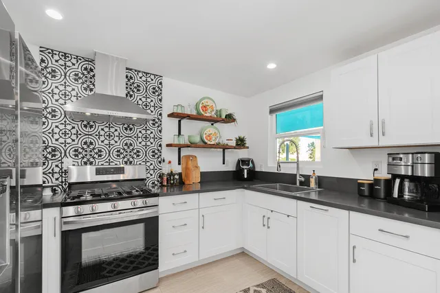 a kitchen with granite countertop white cabinets stainless steel appliances and a sink