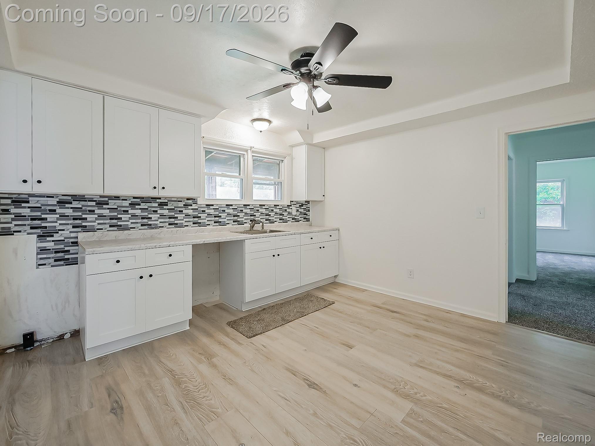 14102 Toepfer Road Warren, MI 48089 - Photo 2 of 39 White cabinetry with black hardware, mosaic tile backsplash, light-toned wood-finish flooring, recessed ceiling, and a ceiling fan with integrated lighting