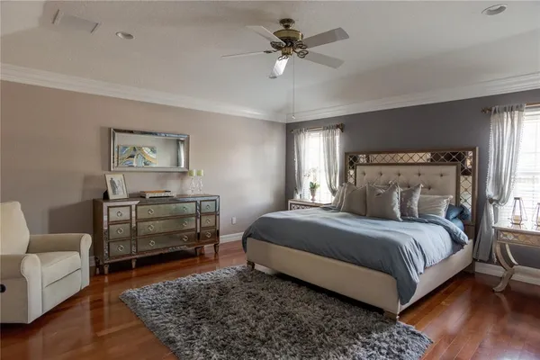 a bedroom with a bed a couch and wooden floor