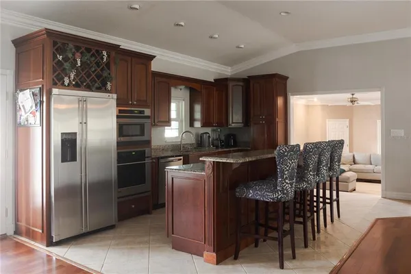 a kitchen with granite countertop a refrigerator a stove a dining table and chairs