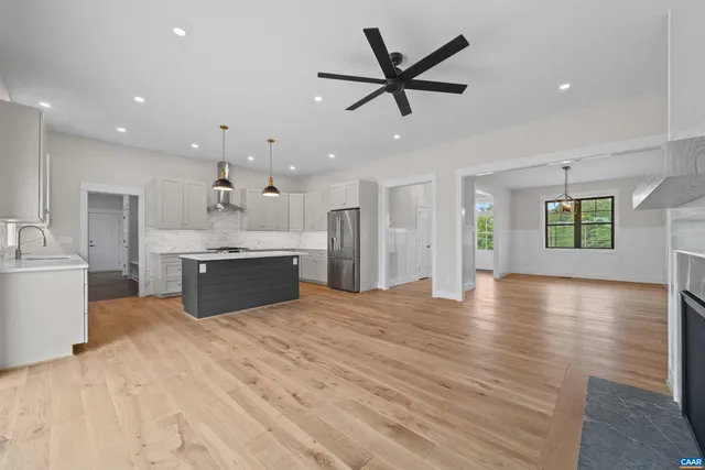 a view of a livingroom with a fireplace a ceiling fan and windows