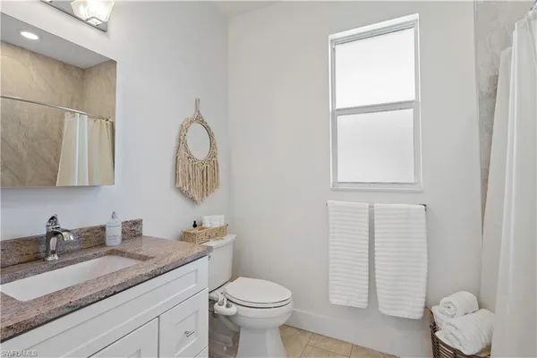 a bathroom with a granite countertop toilet sink and mirror