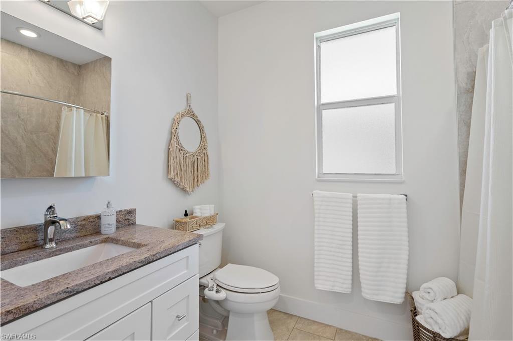 1100 Steeves Avenue Naples, FL 34104 - Photo 15 of 38 a bathroom with a granite countertop toilet sink and mirror