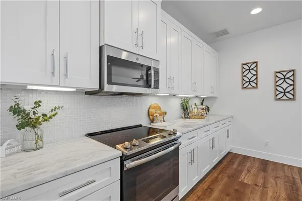 a kitchen with stainless steel appliances white cabinets and a stove top oven