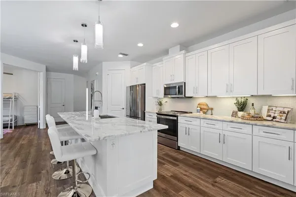 a kitchen with stainless steel appliances kitchen island granite countertop a table chairs sink and cabinets