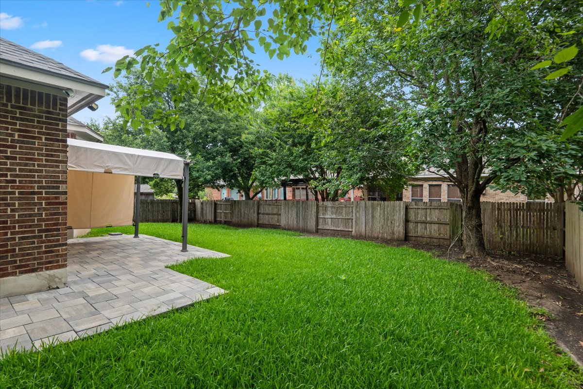 2304 Village View Loop Pflugerville, TX 78660 - Photo 7 of 40 A generous backyard offers a paver patio and ample green space, fully enclosed for privacy.