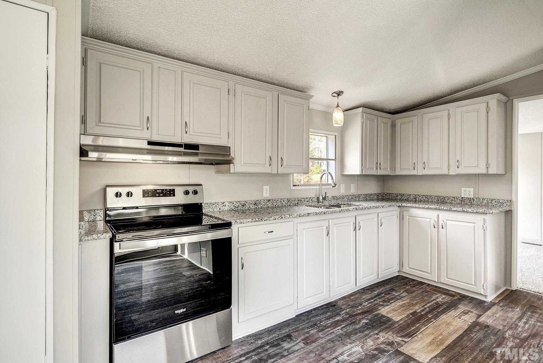 4920 Zacks Mill Road Angier, NC 27501 - Photo 12 of 30 a kitchen with granite countertop white cabinets sink and stainless steel appliances