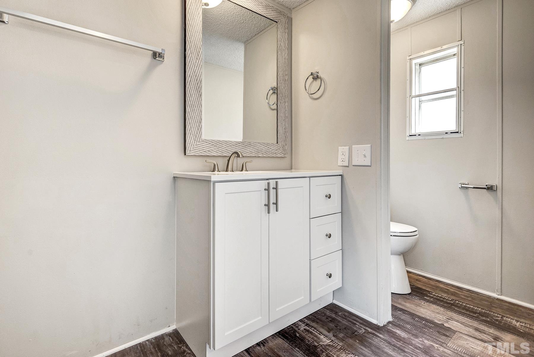 4920 Zacks Mill Road Angier, NC 27501 - Photo 18 of 30 a bathroom with a granite countertop sink a toilet and a window