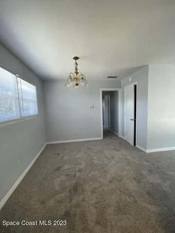 an empty room with a chandelier fan and windows