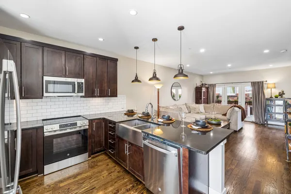 a kitchen with stainless steel appliances granite countertop a sink a stove and a wooden floors