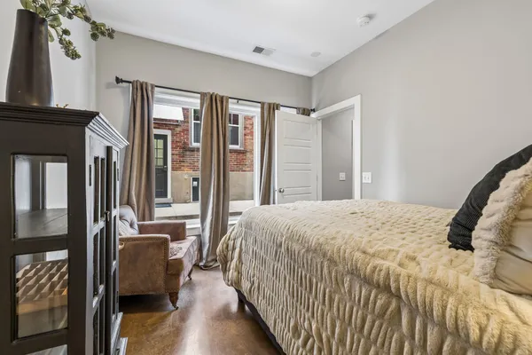 a bedroom with a bed wooden floor and a large mirror