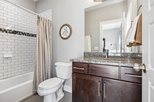 a bathroom with a granite countertop toilet sink and mirror