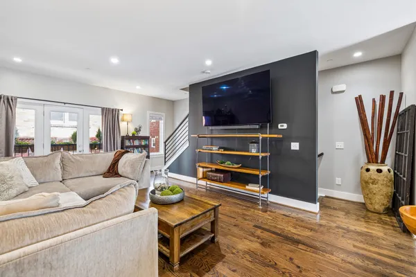 a living room with furniture a flat screen tv and a refrigerator
