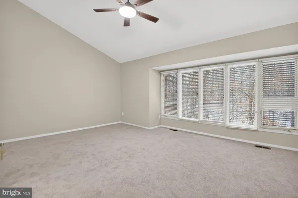 an empty room with chandelier fan and windows