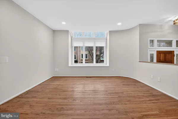 a view of an empty room with window and wooden floor