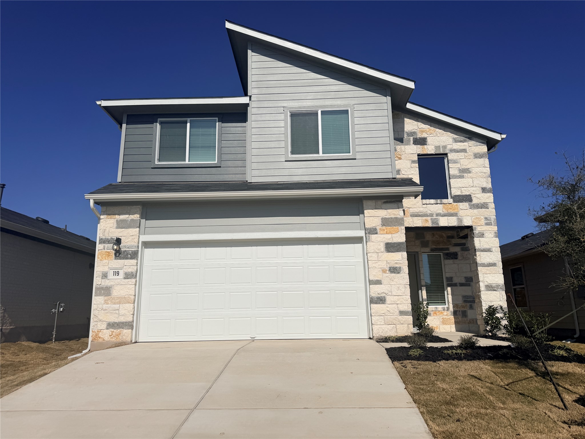 119 Morning Glory Loop Kyle, TX 78640 - Photo 1 of 24 View of front of home with stone siding, concrete driveway, and a garage