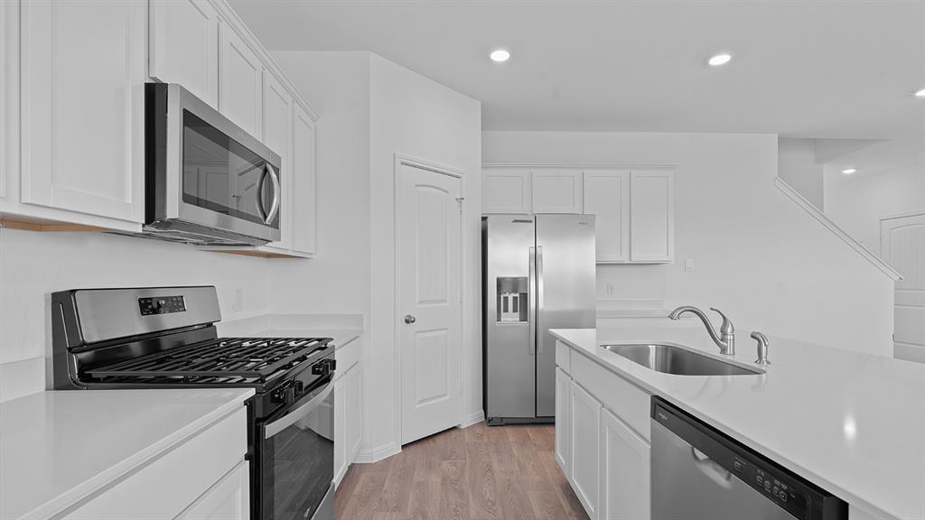 119 Morning Glory Loop Kyle, TX 78640 - Photo 3 of 24 Kitchen with stainless steel appliances, white cabinetry, recessed lighting, light wood-style flooring, and light stone countertops