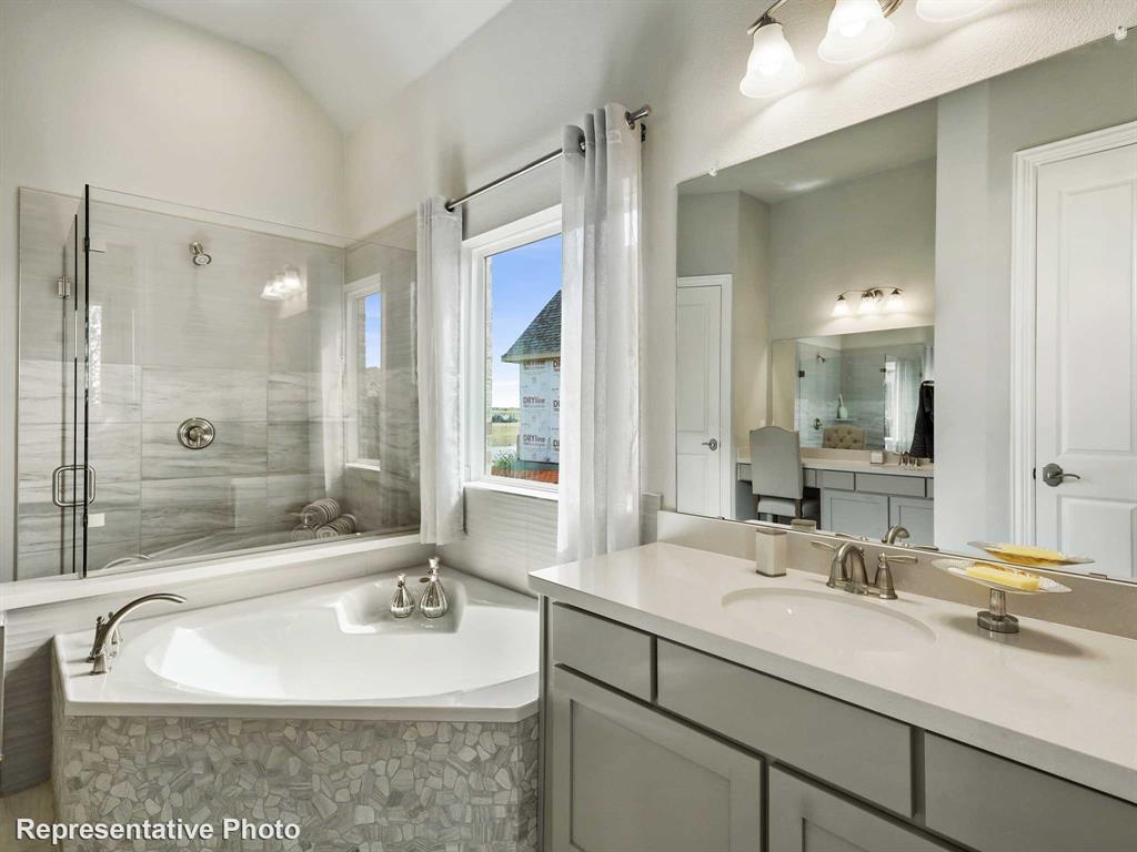 1143 Rothland Lane Red Oak, TX 75154 - Photo 9 of 18 Bathroom featuring a corner soaking tub with pebble-tile surround, a glass-enclosed shower with tile walls, a vanity with a drop-in sink and ample counter space, and a separate vanity area