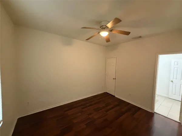 a view of a room with wooden floor and a ceiling fan