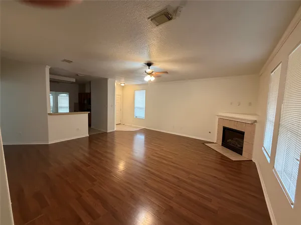 an empty room with wooden floor fireplace and windows