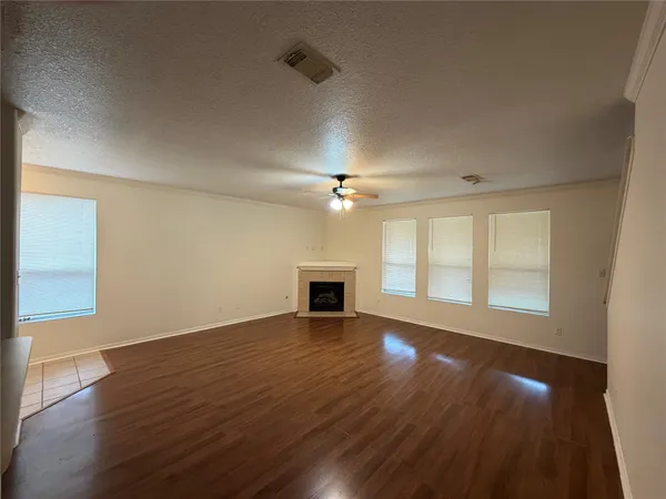 an empty room with wooden floor fireplace and windows