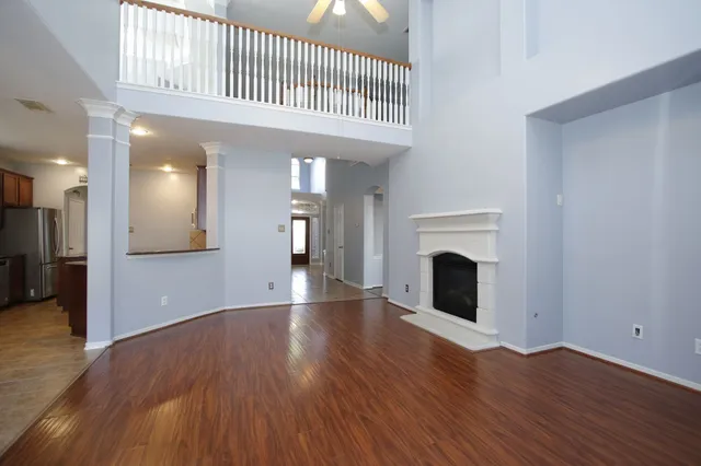 a view of an empty room with wooden floor and a fireplace