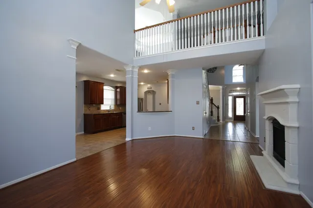 a view of a hallway with wooden floor and a kitchen