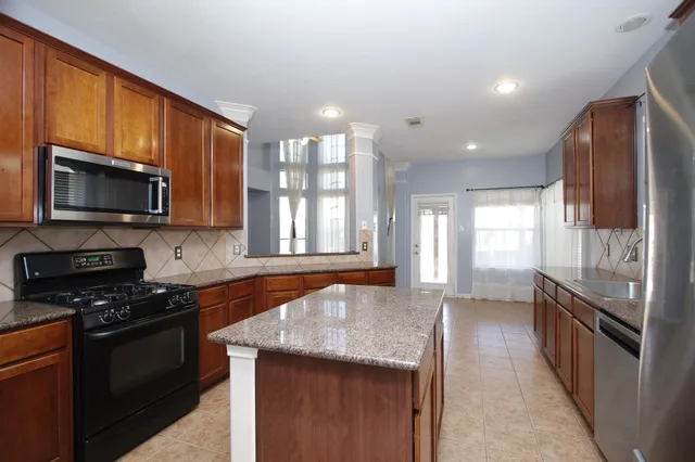 a kitchen with granite countertop stainless steel appliances a stove sink microwave and cabinets