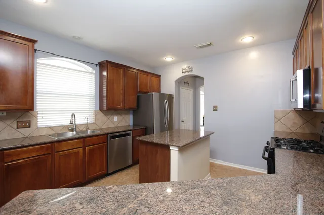 a kitchen with stainless steel appliances granite countertop a sink stove and refrigerator