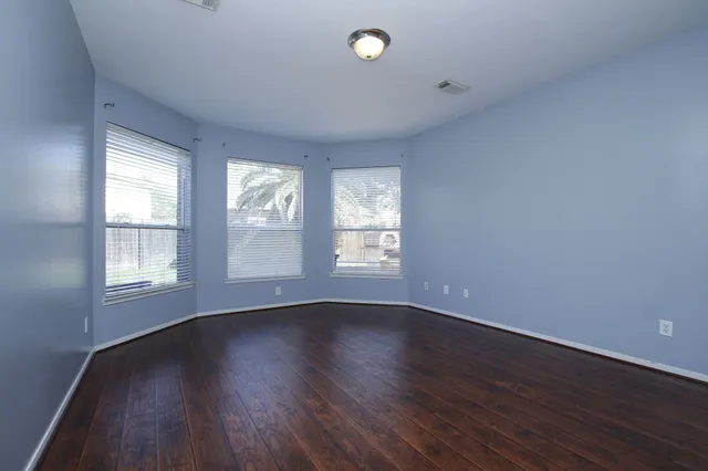 a view of an empty room with wooden floor and window