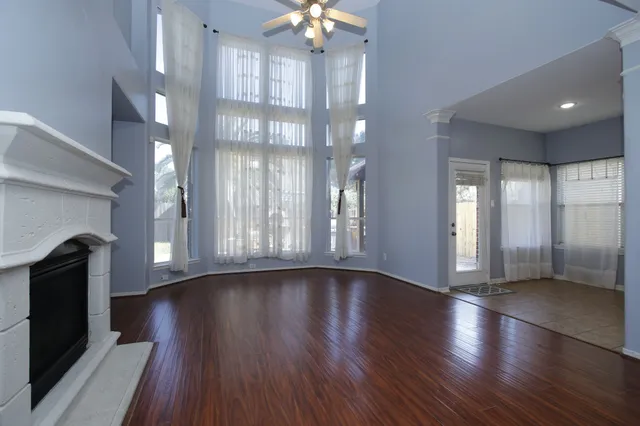 a view of an empty room with wooden floor and a fireplace