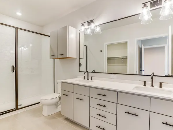 a bathroom with a double vanity sink toilet mirror and shower