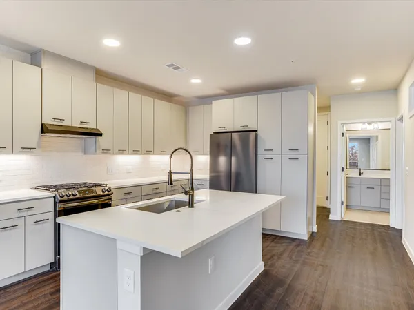 a kitchen with stainless steel appliances a sink a stove a refrigerator and cabinets