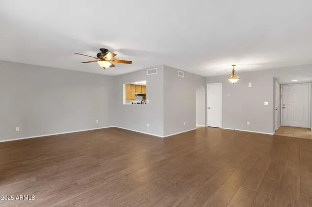 a view of an empty room with wooden floor and a window