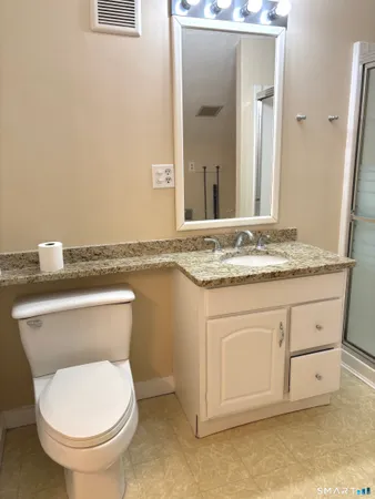 a bathroom with a granite countertop toilet sink and mirror