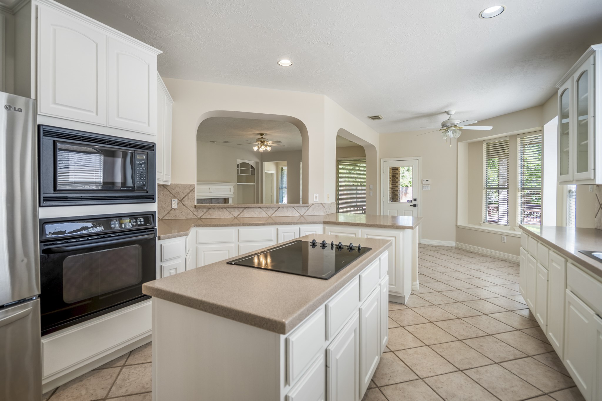 1322 Cardigan Bay Circle Spring, TX 77379 - Photo 17 of 50 The island features an electric cooktop, an oven, microwave, and refrigerator (which stays) a breakfast bar with diagonal tile, providing a clear boundary between the cooking and living areas while remaining open for conversation.