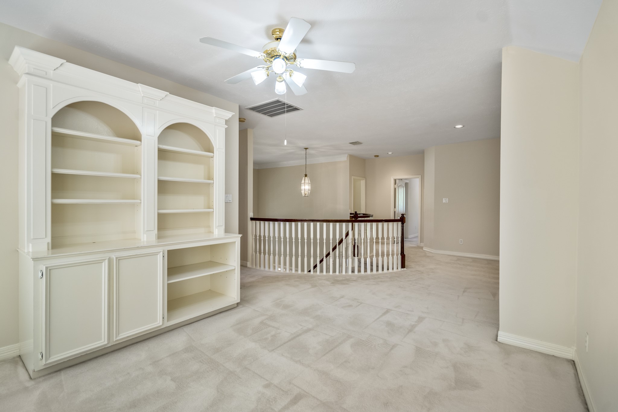 1322 Cardigan Bay Circle Spring, TX 77379 - Photo 30 of 50 At the top of the stairs you will find a custom white wall unit, with arched design on the upper shelves and a mix of closed cabinets and open shelving, ideal for your entertainment media storage.