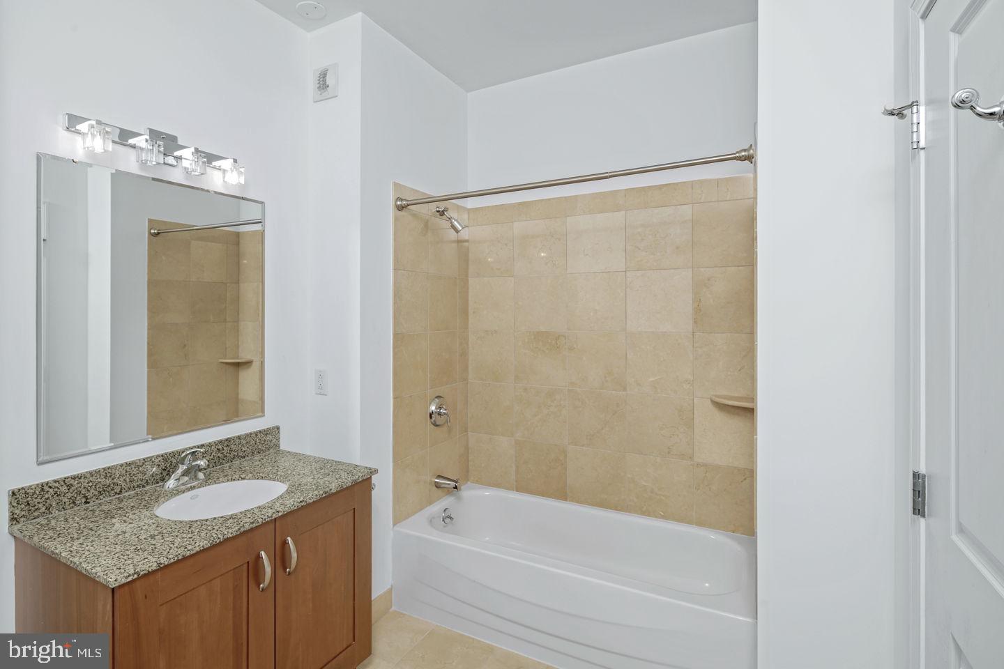 901 North Penn Street, Unit R1802 Philadelphia, PA 19123 - Photo 18 of 32 a bathroom with a granite countertop sink a mirror and a bathtub