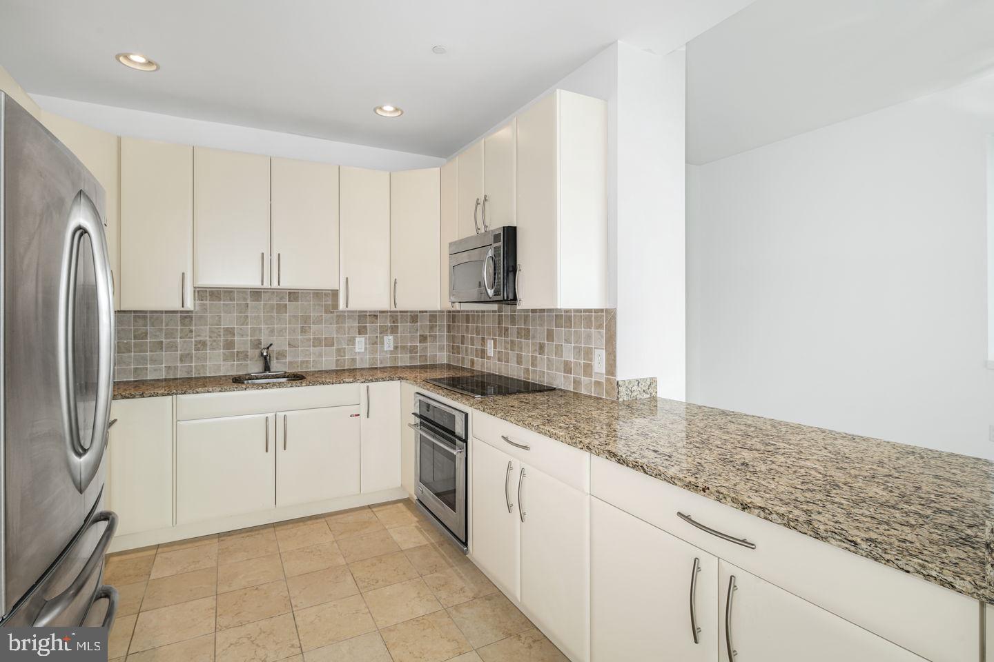 901 North Penn Street, Unit R1802 Philadelphia, PA 19123 - Photo 10 of 32 a kitchen with granite countertop white cabinets and white appliances