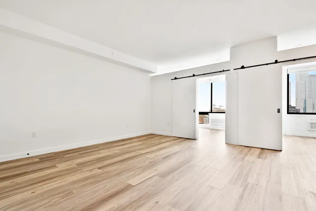 a view of an empty room with wooden floor and a window