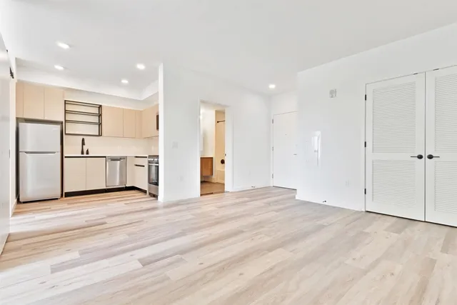 a view of a kitchen with refrigerator and white wooden cabinets