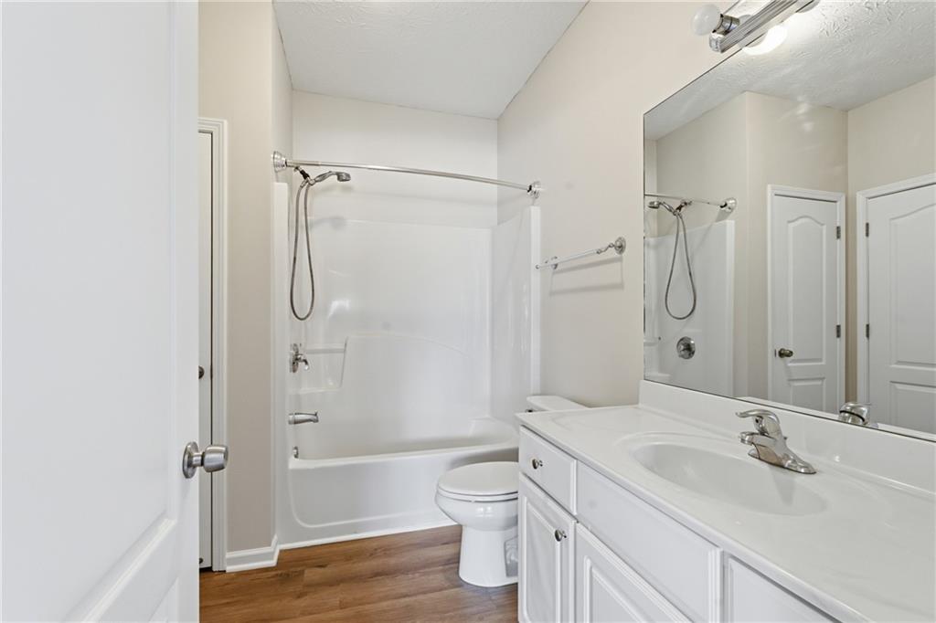 4533 Caleb Crossing, Unit 18 Powder Springs, GA 30127 - Photo 19 of 24 a bathroom with a granite countertop sink toilet a shower and a bathtub