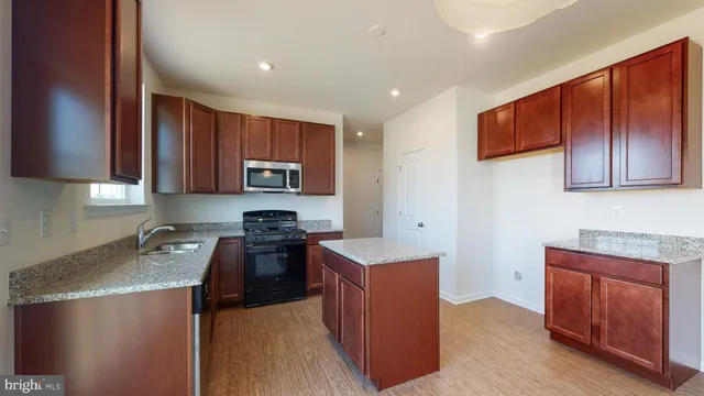 a kitchen with stainless steel appliances granite countertop wooden cabinets a stove top oven a sink and dishwasher
