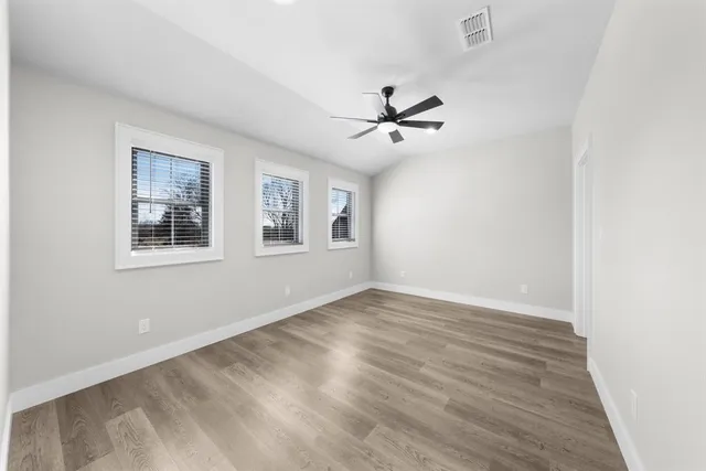 a view of empty room with wooden floor and fan