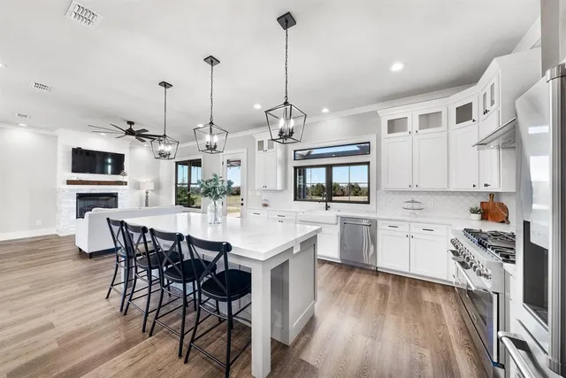 a kitchen with stainless steel appliances kitchen island granite countertop a sink a stove a dining table and chairs with wooden floor